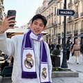 一位年轻男子穿着皇马围巾在马德里街头拍照